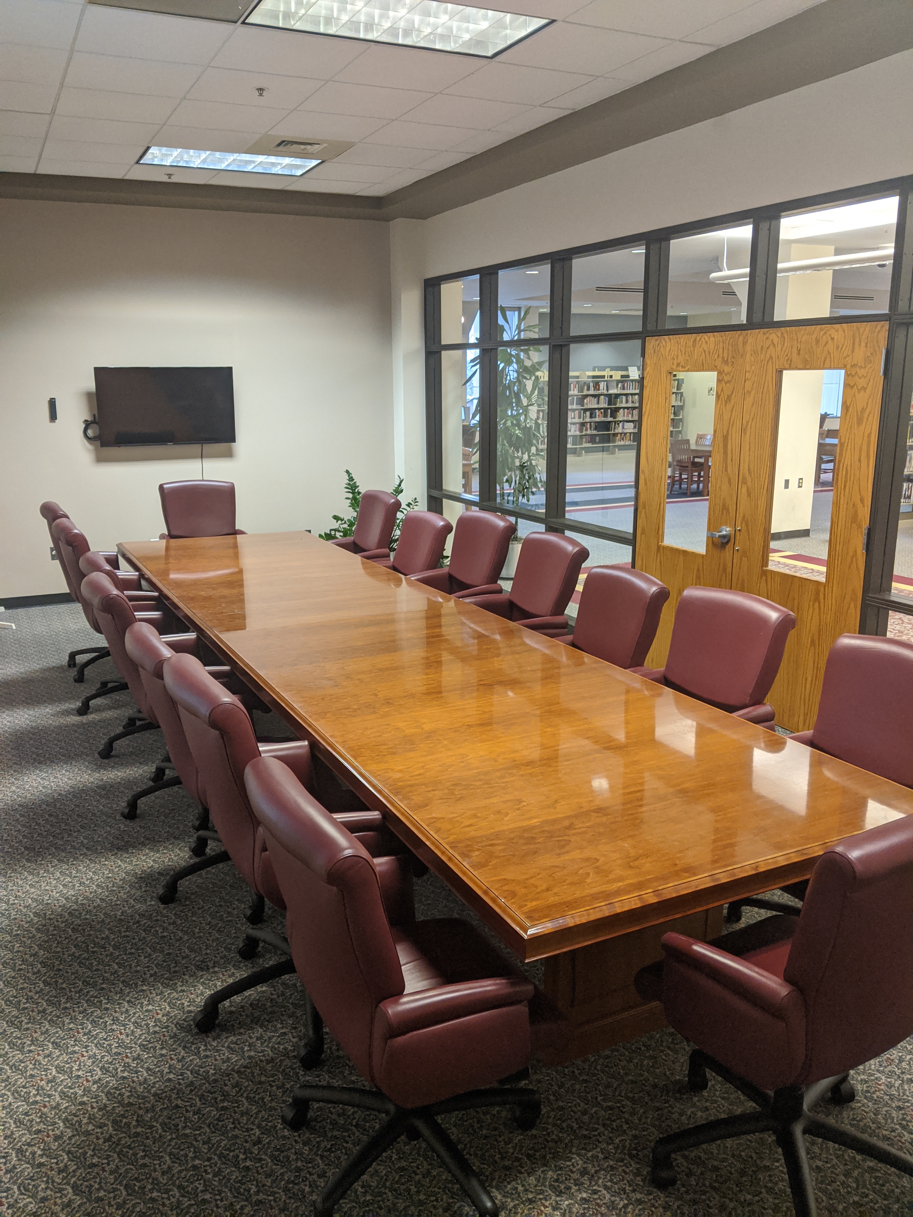 Room photo of the Wren Meeting Room showing long conference table with chairs all around it and a mounted television
