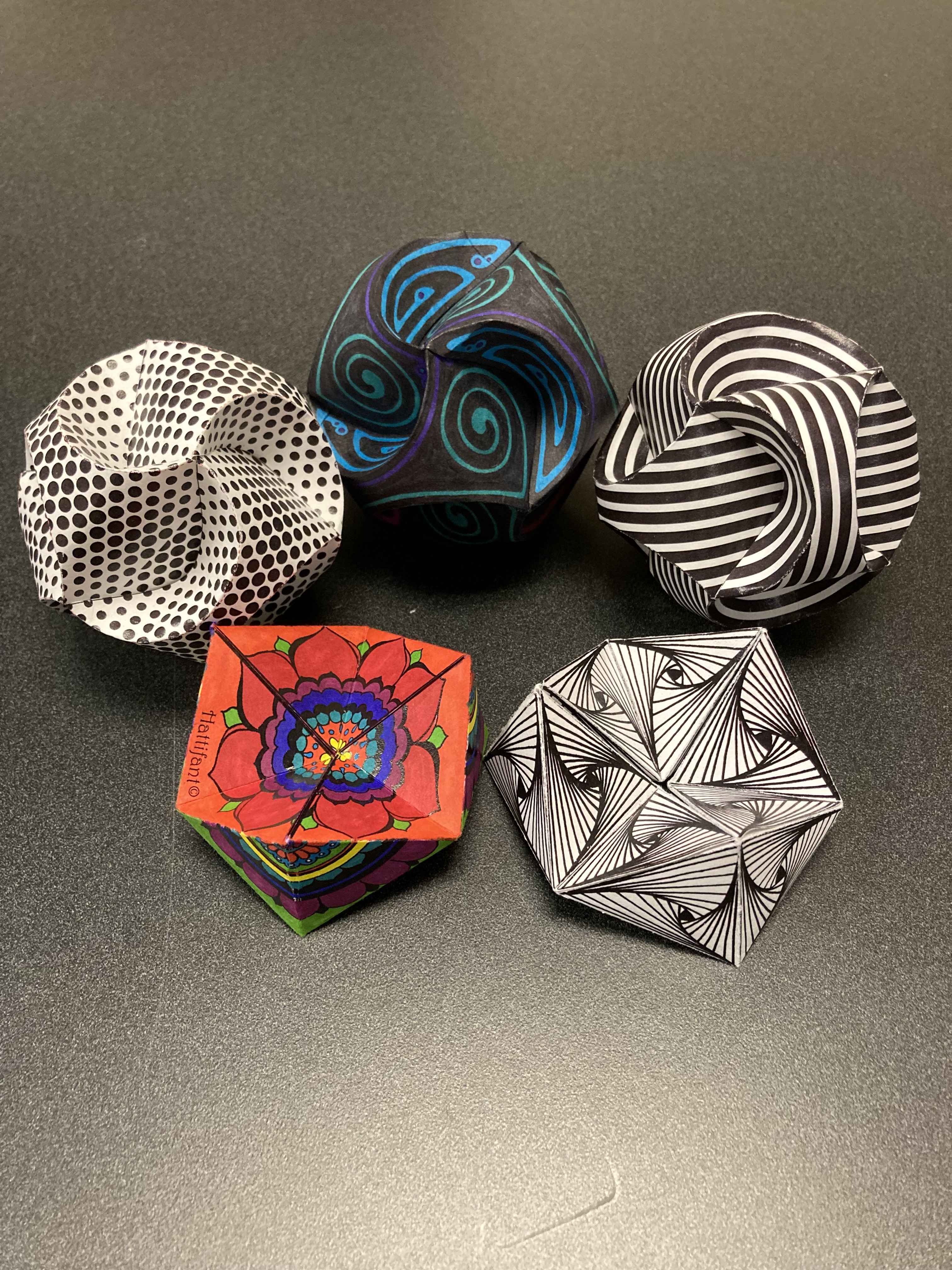 Five paper triskeles of varying patterns.