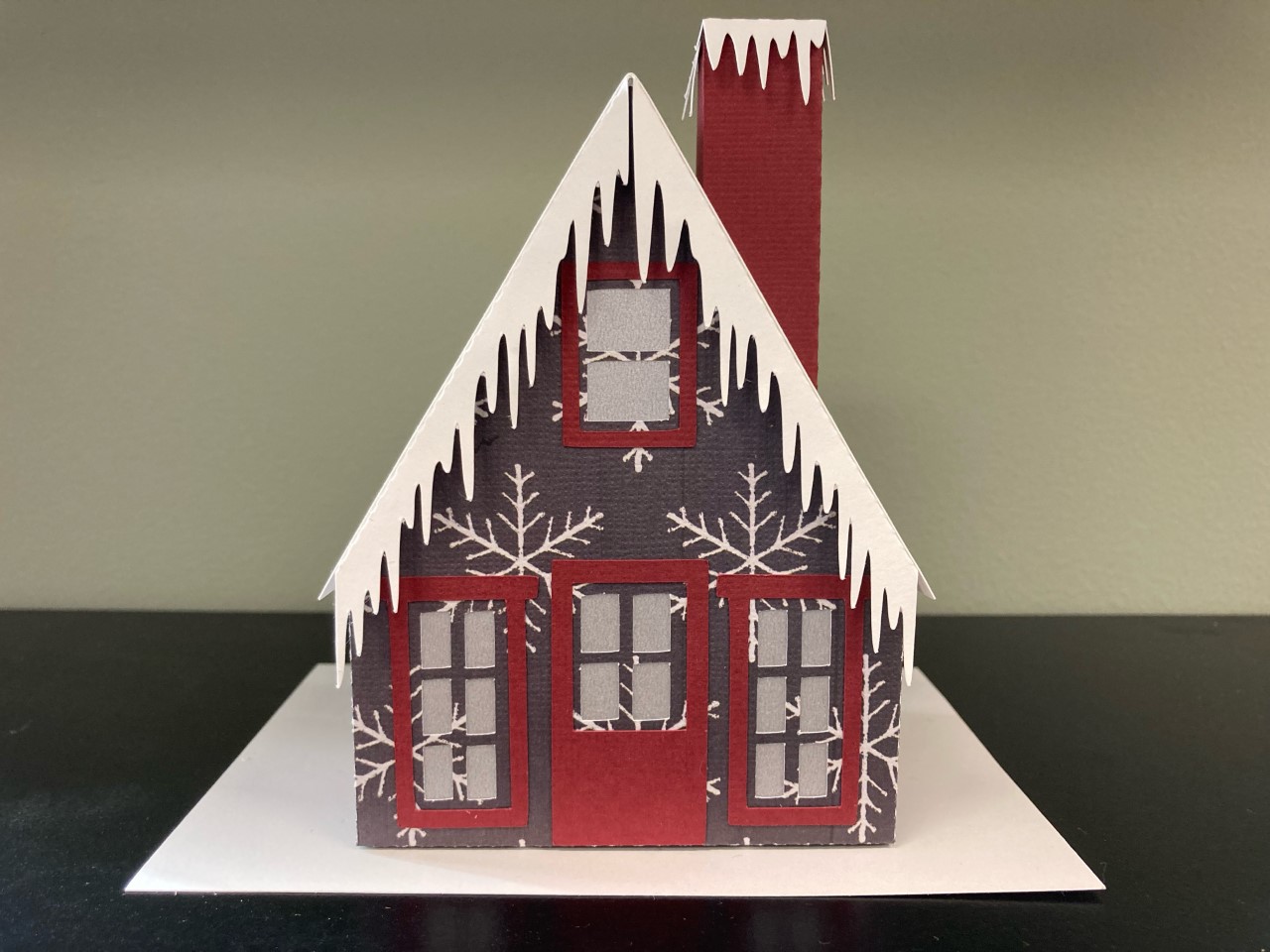 a red house with decorative snow and ice on it made out of paper
