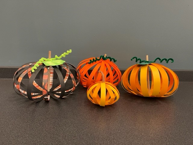 Four paper pumpkins constructed of cardstock paper with green leaves