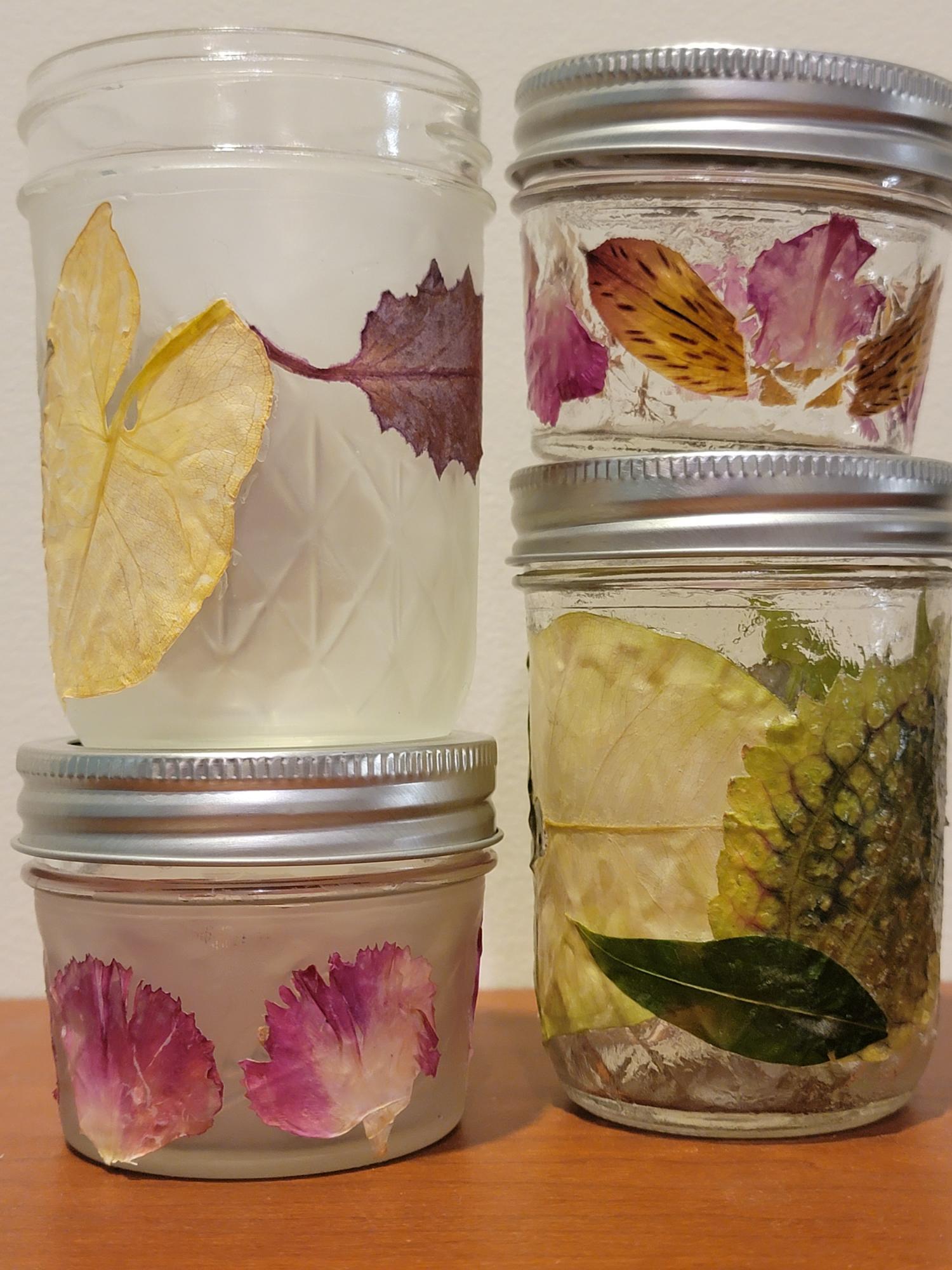 4 jars with leaves and flower petals on them