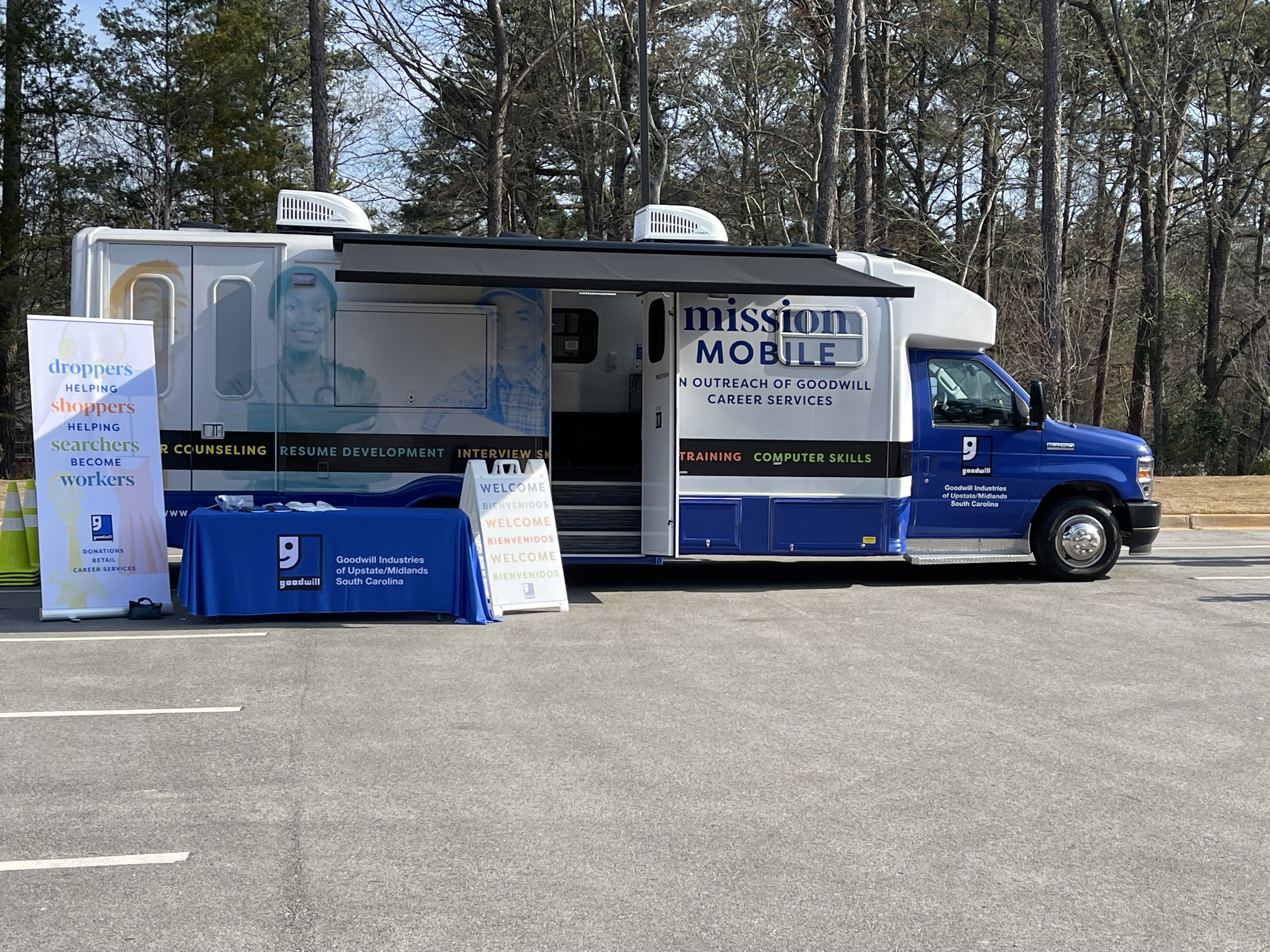 Goodwill Mission Mobile bus set up for business with informational signs and table
