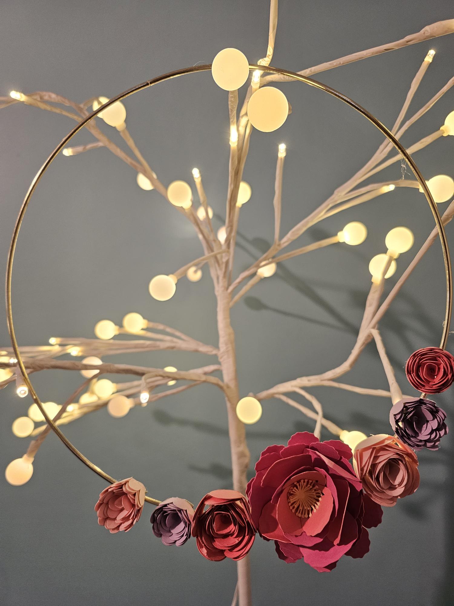 gold hoop with flowers attached on lit tree