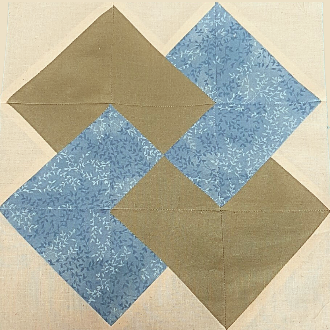 a green, white, and blue quilt square in the "card trick" arrangement 