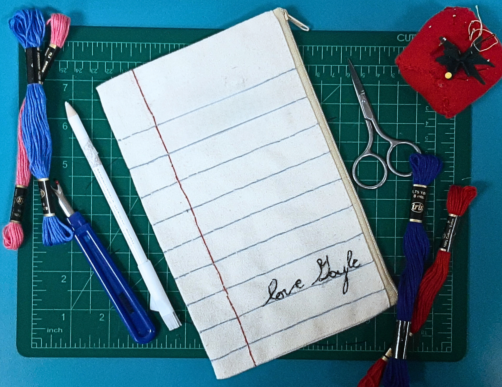 An embroidered pencil pouch with a notebook paper design on the front. 