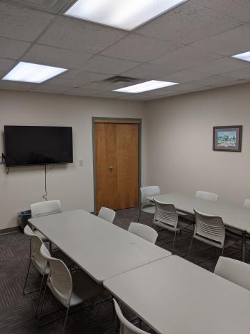 Room photo of Iva Meeting Room with tables placed in two parallel rows and a mounted television