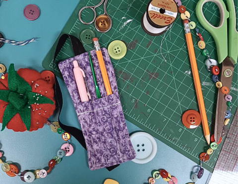 a purple pencil holder with a pen, pencil, and crochet hook in the pockets 